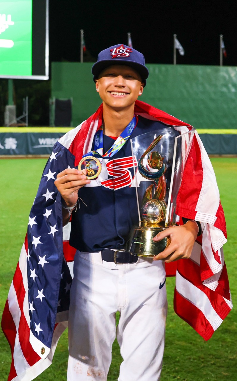 Anthony Ramon in his USA uniform, draped in an American flag and holding a trophy and medal